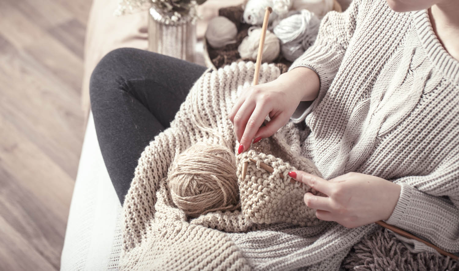 Vintage wooden spokes and yarn in the hands of a woman on a cozy sofa . Still life photo. The concept of comfort